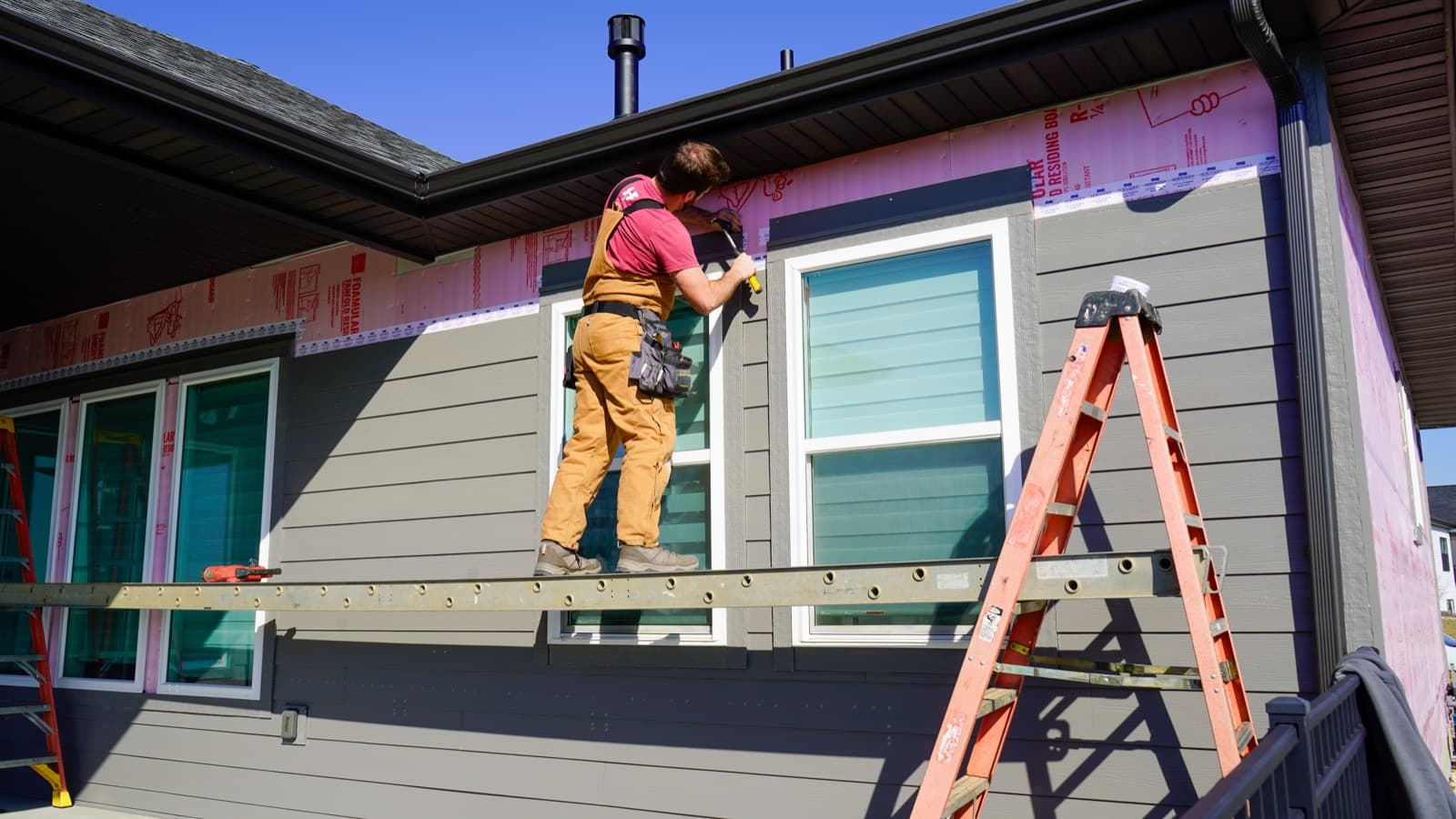 An H&F installer fitting new lap siding on a home