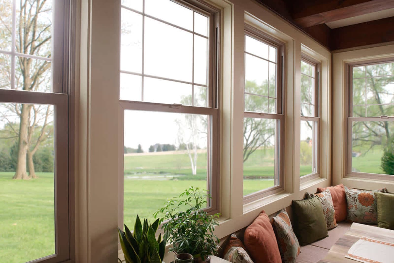 A bright sunroom lined with new double-hung windows overlooking a green lawn